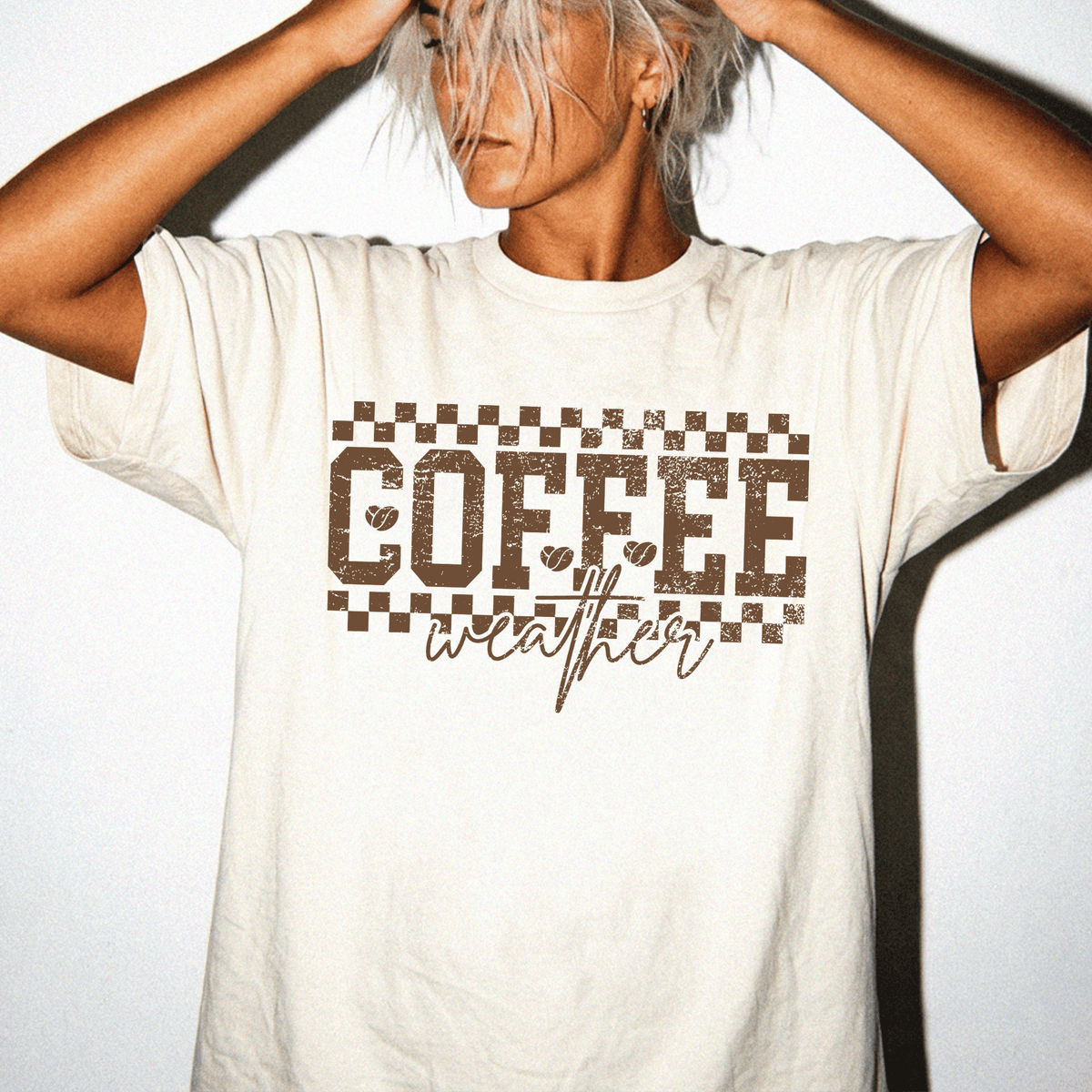 A person wearing a white t-shirt with the text "COFFEE weather" printed on it.