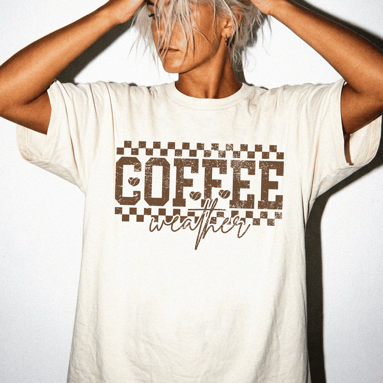 A person wearing a white t-shirt with the text "COFFEE weather" printed on it.