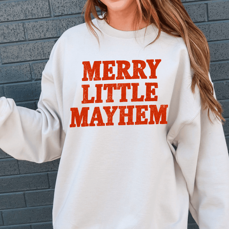 A white sweatshirt with the text "MERRY LITTLE MAYHEM" printed on it in red.