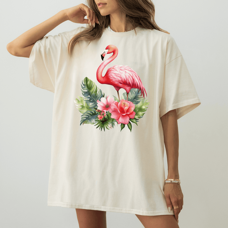 A woman wearing a white t-shirt with a pink flamingo and tropical flowers printed on it.