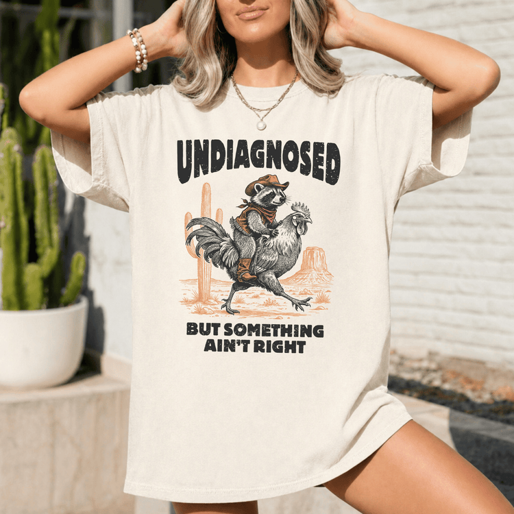 A woman wearing a white t-shirt with a graphic design featuring a raccoon riding a rooster.