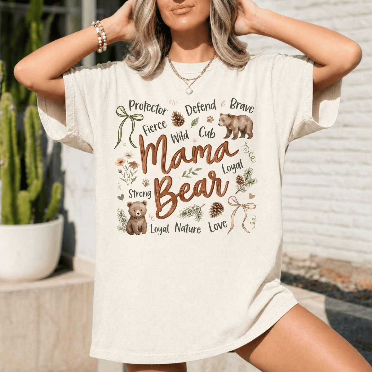 A woman wearing a white t-shirt with a graphic design featuring a bear and various words related to motherhood and nature.
