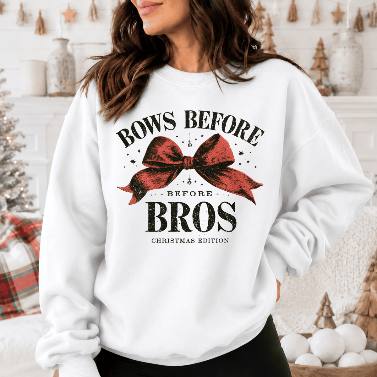 A woman wearing a white sweatshirt with a graphic design that says "BOWS BEFORE BROS CHRISTMAS EDITION".