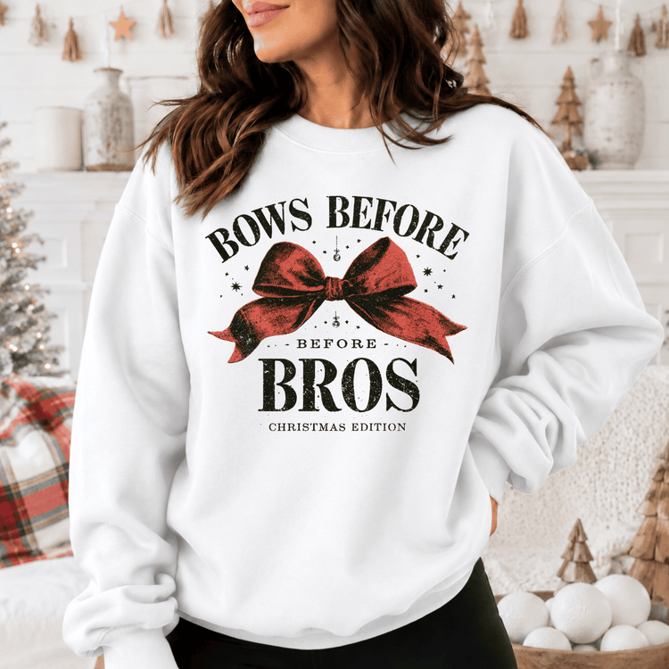 A woman wearing a white sweatshirt with a graphic design that says "BOWS BEFORE BROS CHRISTMAS EDITION".
