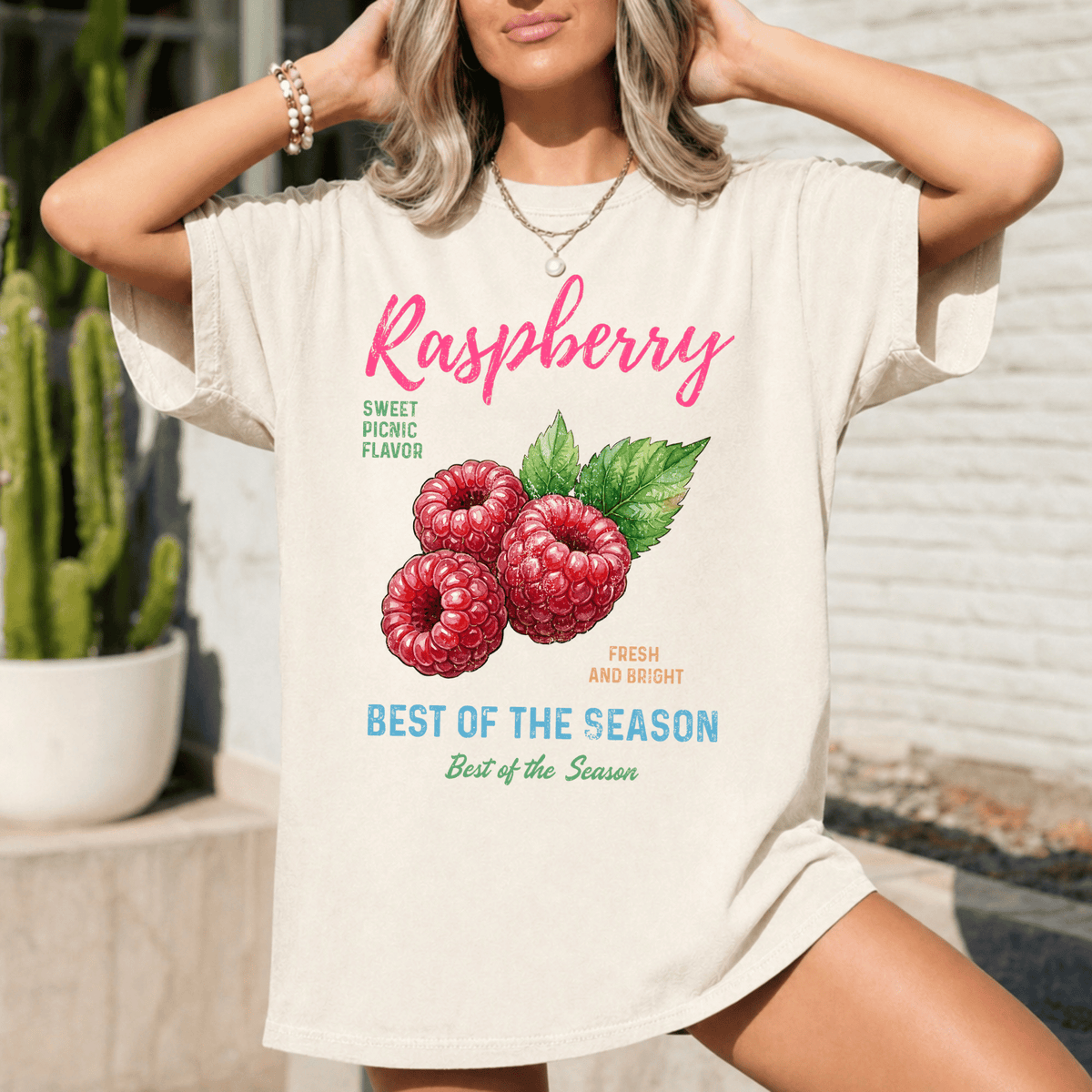 A woman wearing a white t-shirt with a graphic of raspberries and text promoting raspberry flavor.