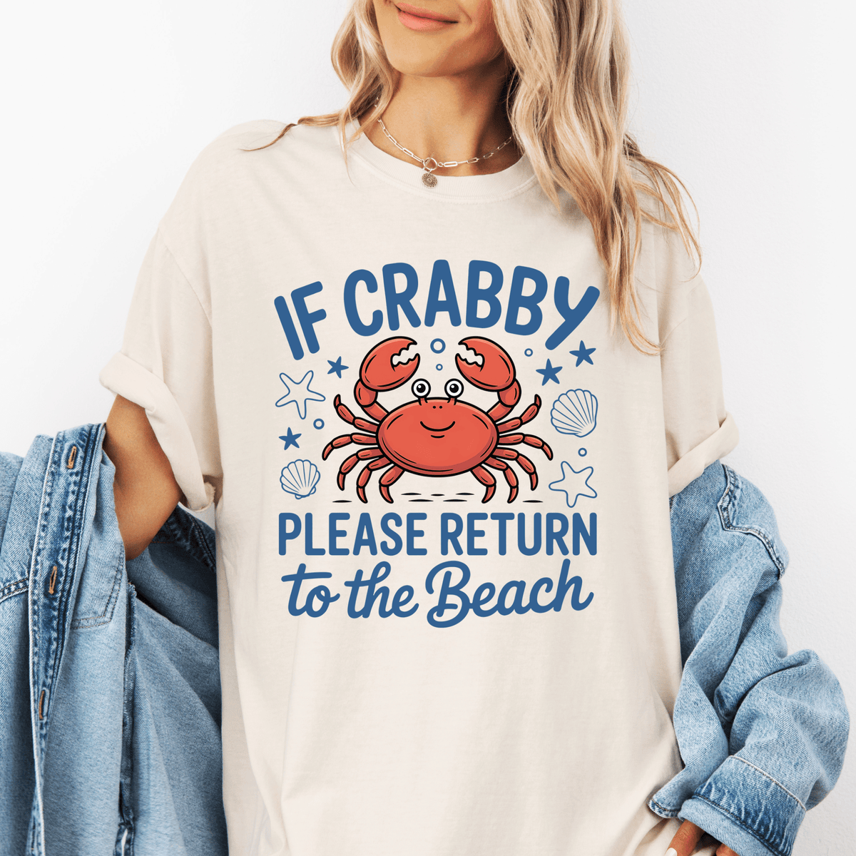 A woman wearing a white t-shirt with a graphic design of a crab and the text "IF CRABBY PLEASE RETURN TO THE BEACH" printed on it.