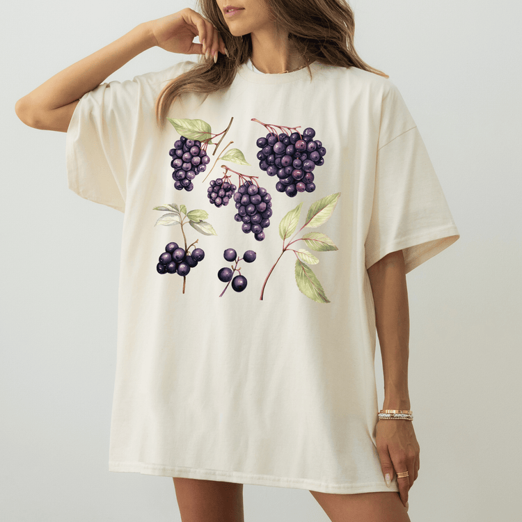 A woman wearing a white t-shirt with a graphic design of purple grapes and leaves.