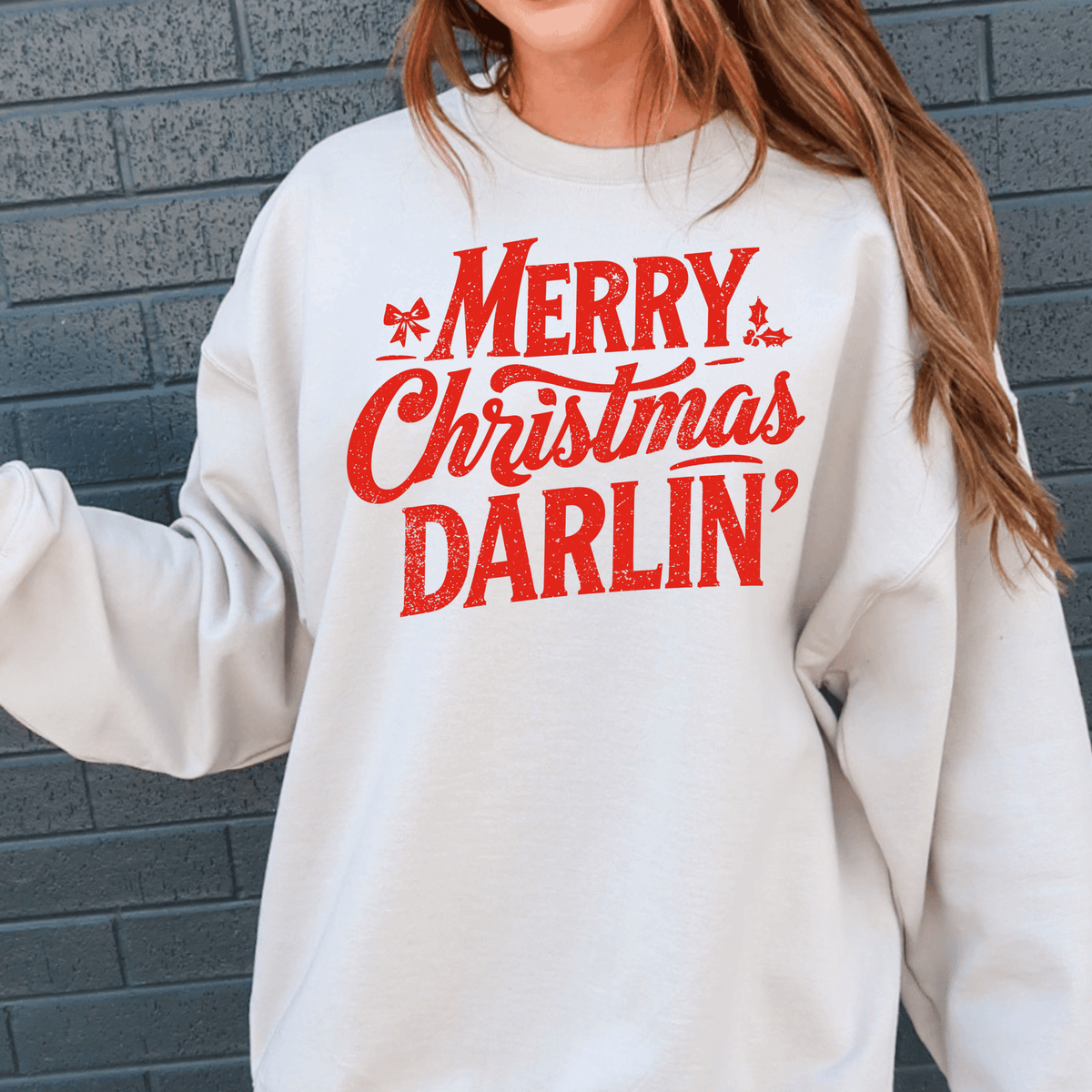 A person wearing a white sweatshirt with the text "Merry Christmas Darlin" printed on it.