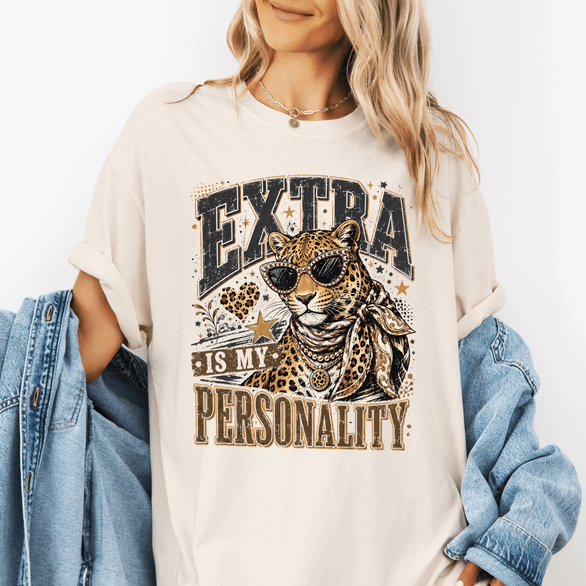 A woman wearing a white t-shirt with a graphic design of a leopard wearing sunglasses and the text "EXTRA IS MY PERSONALITY" printed on it.