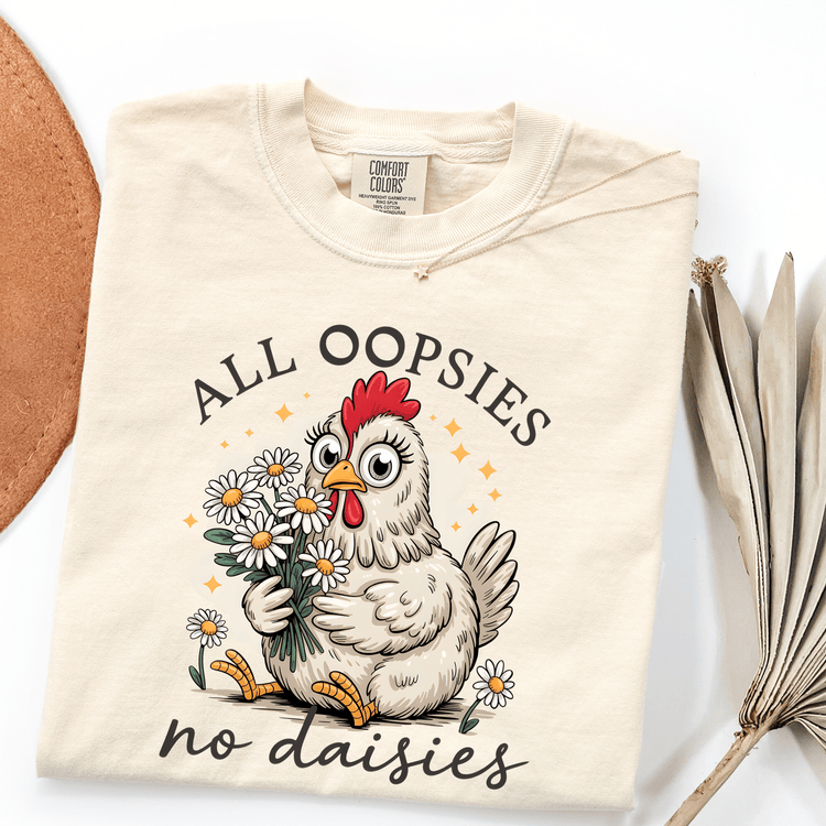 A white t-shirt with a cartoon chicken holding flowers and the text "ALL OOPSIES no daisies" printed on it.