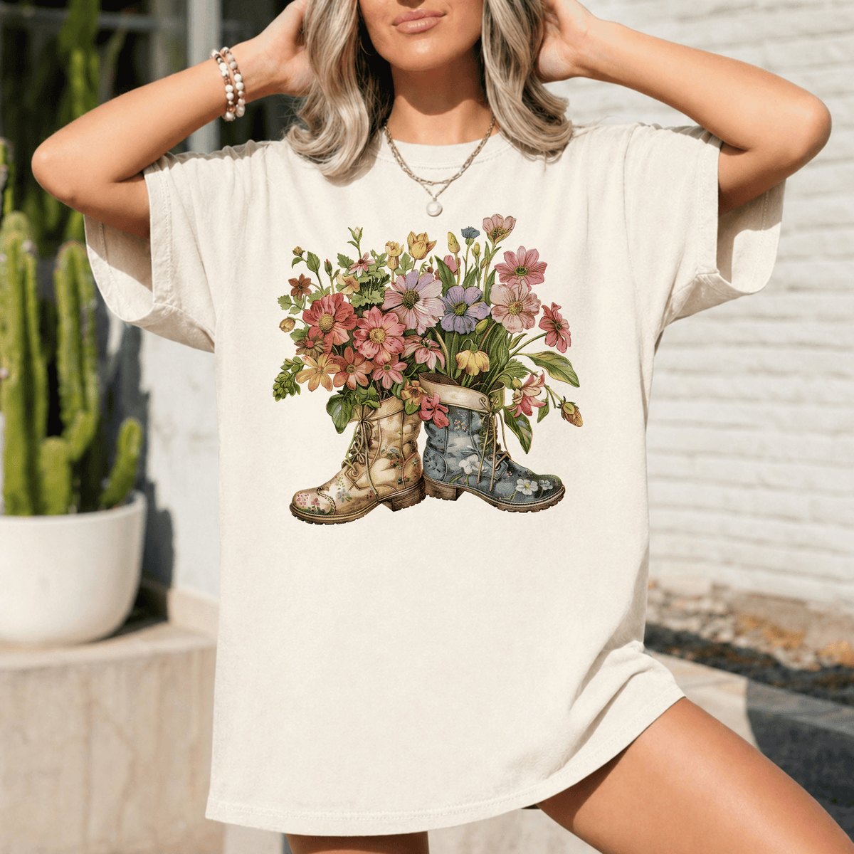 A woman wearing a white t-shirt with a floral design of two boots, one blue and one green, holding a bouquet of colorful flowers.