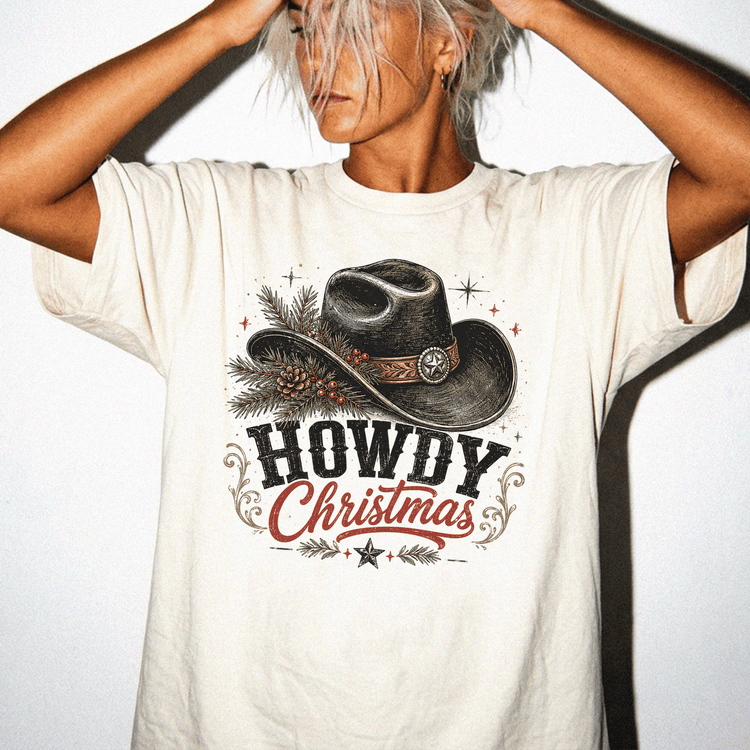 A woman wearing a white t-shirt with a graphic design of a cowboy hat and the text "HOWDY CHRISTMAS" printed on it.