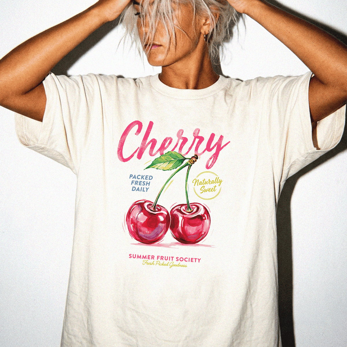 A person wearing a white t-shirt with a graphic design of cherries and text related to fruit.