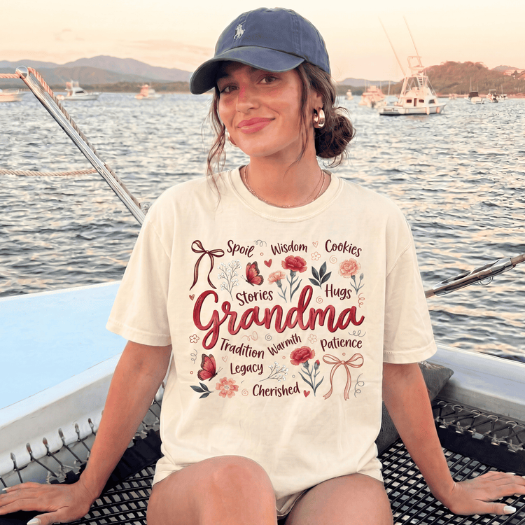 A woman wearing a t-shirt with a design that says "Grandma" and various other words, sitting on a boat in the water.