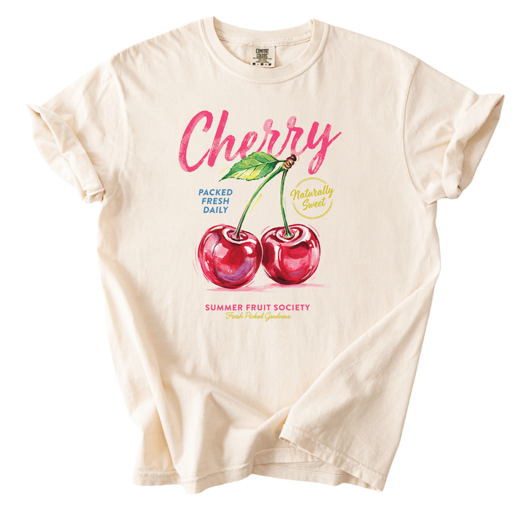 A white t-shirt with a graphic design featuring two cherries and text related to fresh fruit.