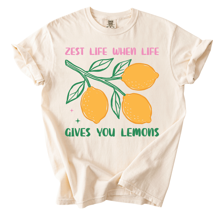 a white t-shirt with a graphic design of lemons and leaves, along with the text "ZEST LIFE WHEN LIFE GIVES YOU LEMONS" printed on it.