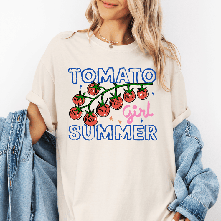 A woman wearing a white t-shirt with a graphic design of tomatoes and the text "TOMATO GIRL SUMMER" printed on it.