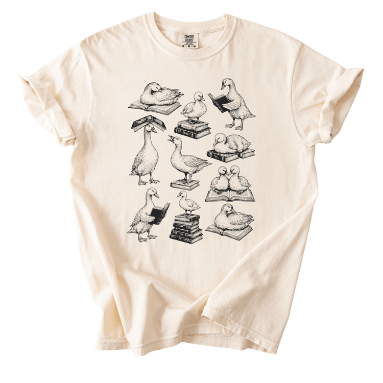 A t-shirt with a graphic design depicting various ducks engaged in different activities, such as reading books and sitting on stacks of books.
