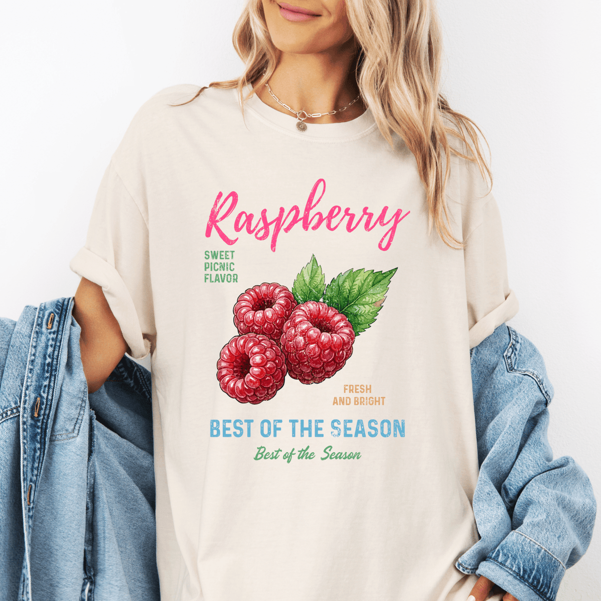A woman wearing a white t-shirt with a graphic of raspberries and text promoting raspberry flavor.