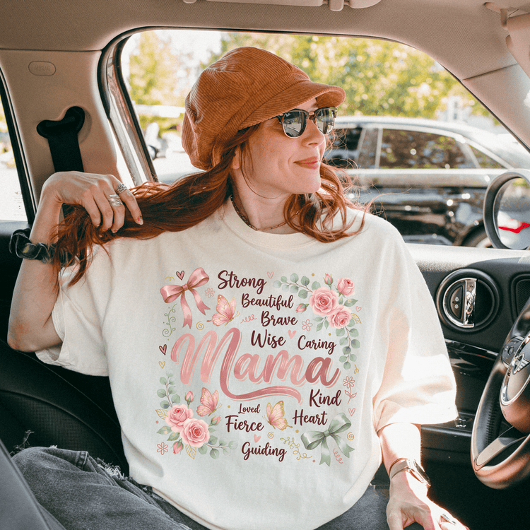 A woman wearing a white t-shirt with a floral design and text, sitting in a car.