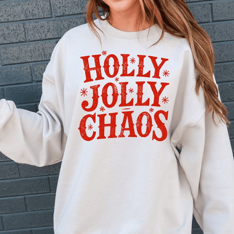 A person wearing a white sweatshirt with the text "Holly Jolly Chaos" printed on it.
