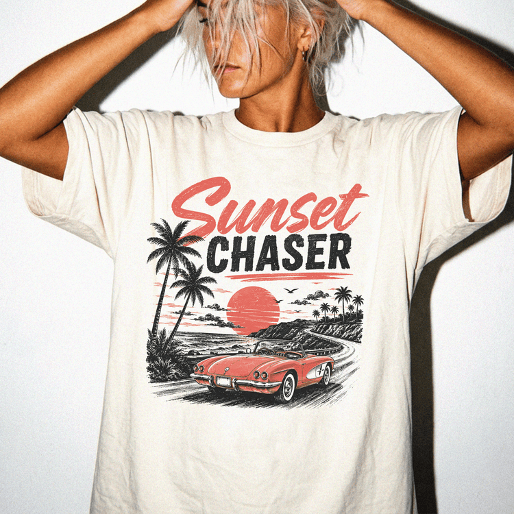 A person wearing a white t-shirt with a graphic design depicting a red sports car and palm trees, along with the text "Sunset Chaser".