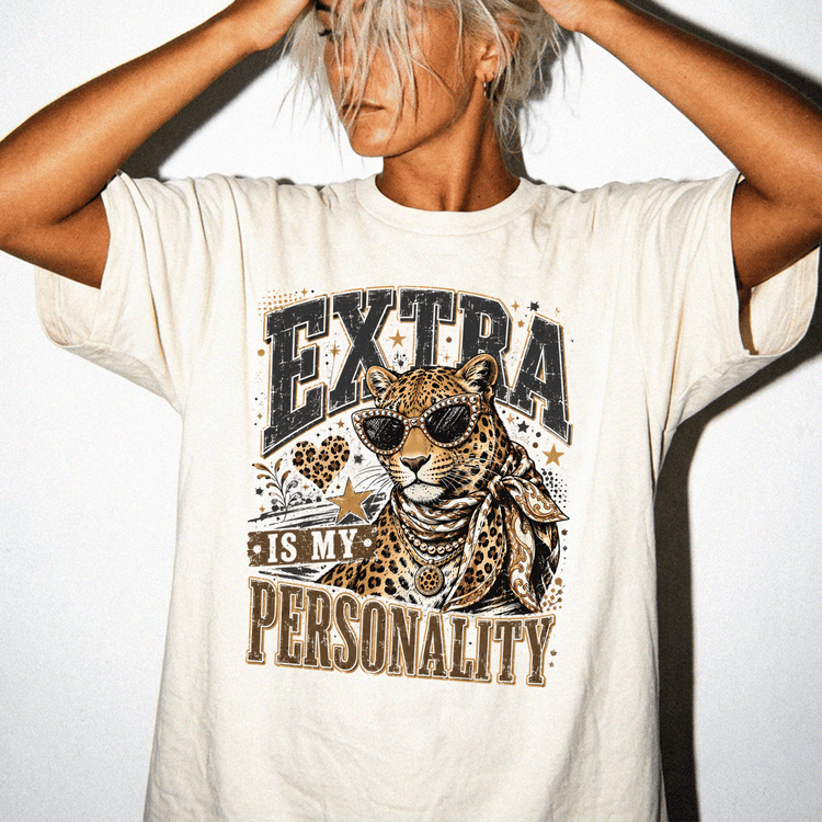 A person wearing a white t-shirt with a graphic design of a leopard and the text "EXTRA IS MY PERSONALITY" printed on it.
