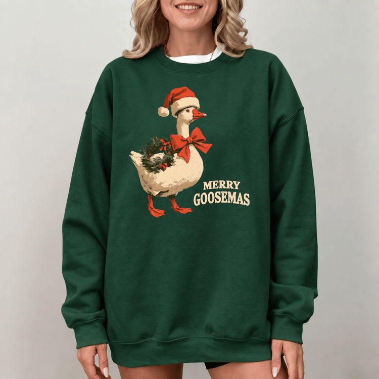 A woman wearing a green sweatshirt with a graphic of a goose wearing a Santa hat and holding a Christmas wreath.