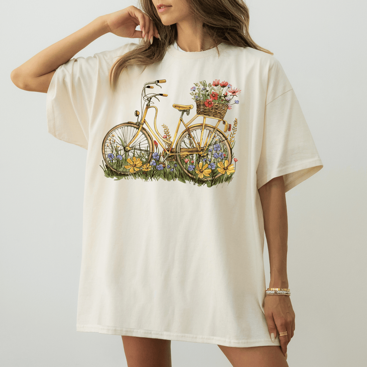 A woman wearing a white t-shirt with a bicycle graphic and flowers on the seat.