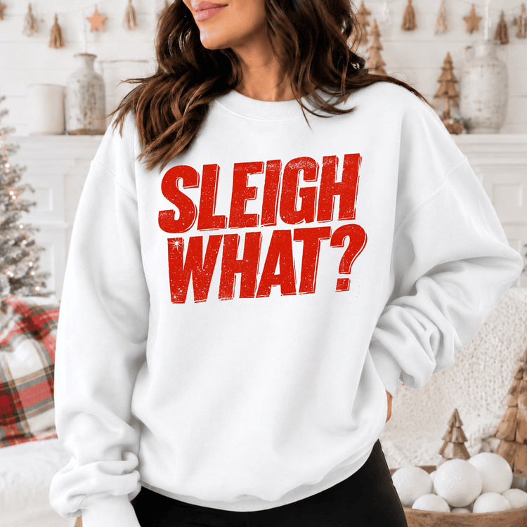 A woman wearing a white sweatshirt with the text "SLEIGH WHAT?" printed on it.