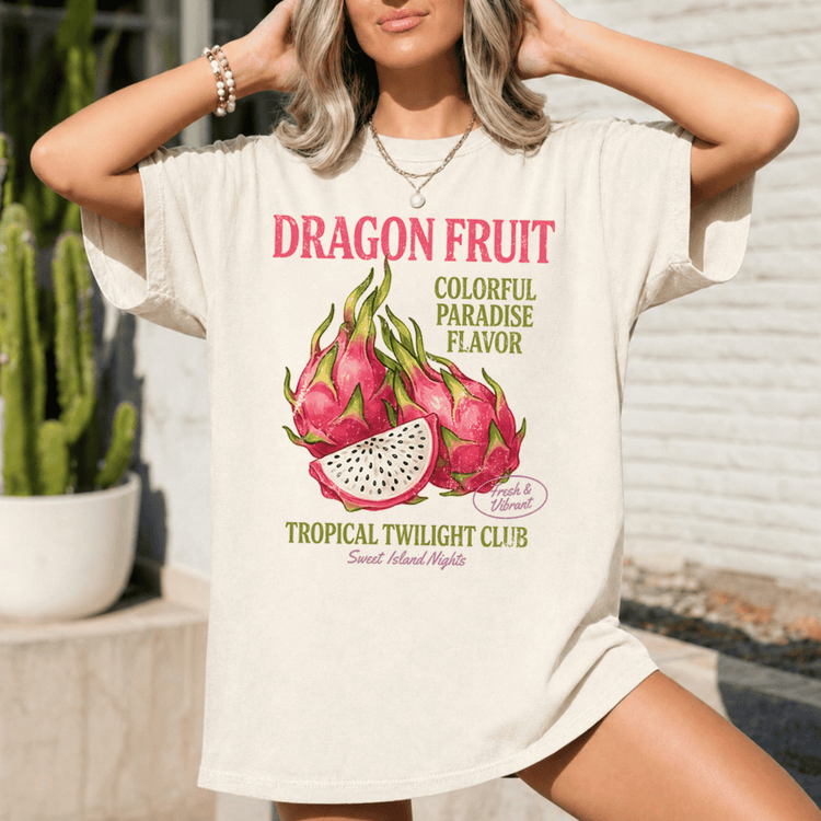 A woman wearing a white t-shirt with a graphic design of dragon fruit and tropical flowers, along with text promoting the Dragon Fruit Tropical Twilight Club.