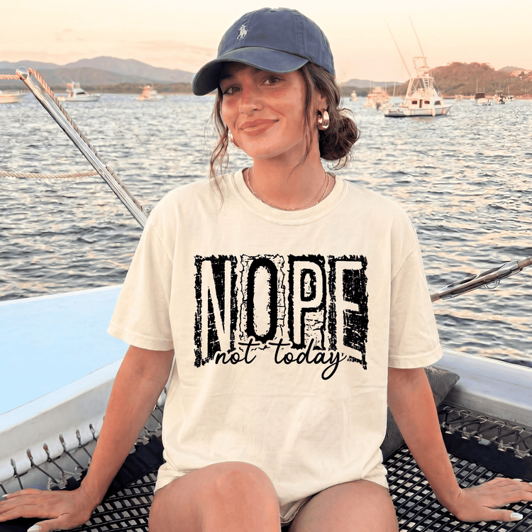A woman wearing a white t-shirt with the text "NOPE not today" is sitting on a boat, smiling and looking at the camera.