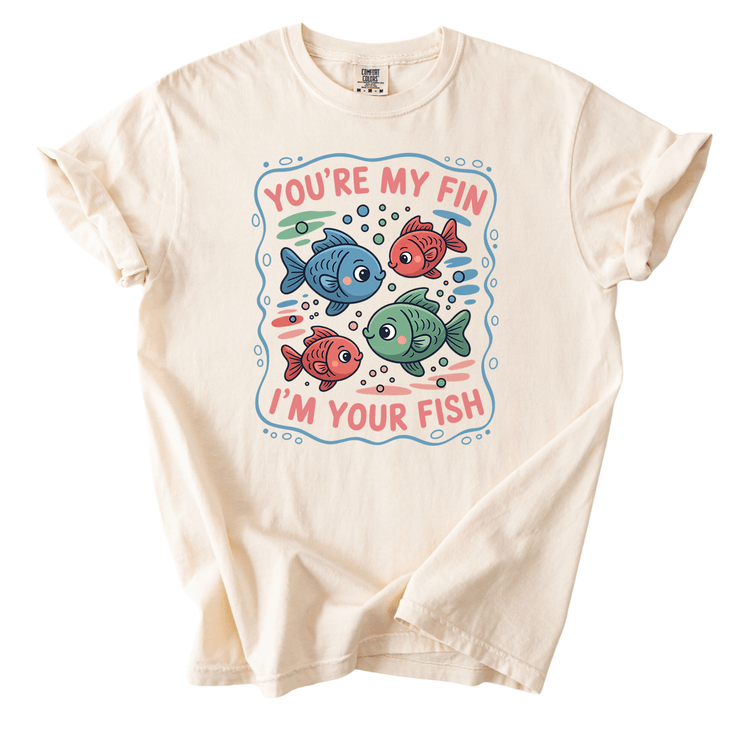 A white t-shirt with a colorful graphic design featuring three fish and the text "You're my fin, I'm your fish" printed on it.