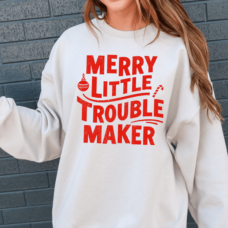 A white sweatshirt with red text that says "MERRY LITTLE TROUBLE MAKER".