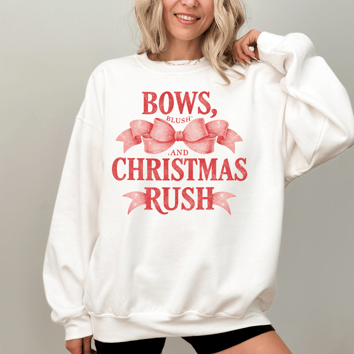 A woman wearing a white sweatshirt with a red bow and text printed on it.
