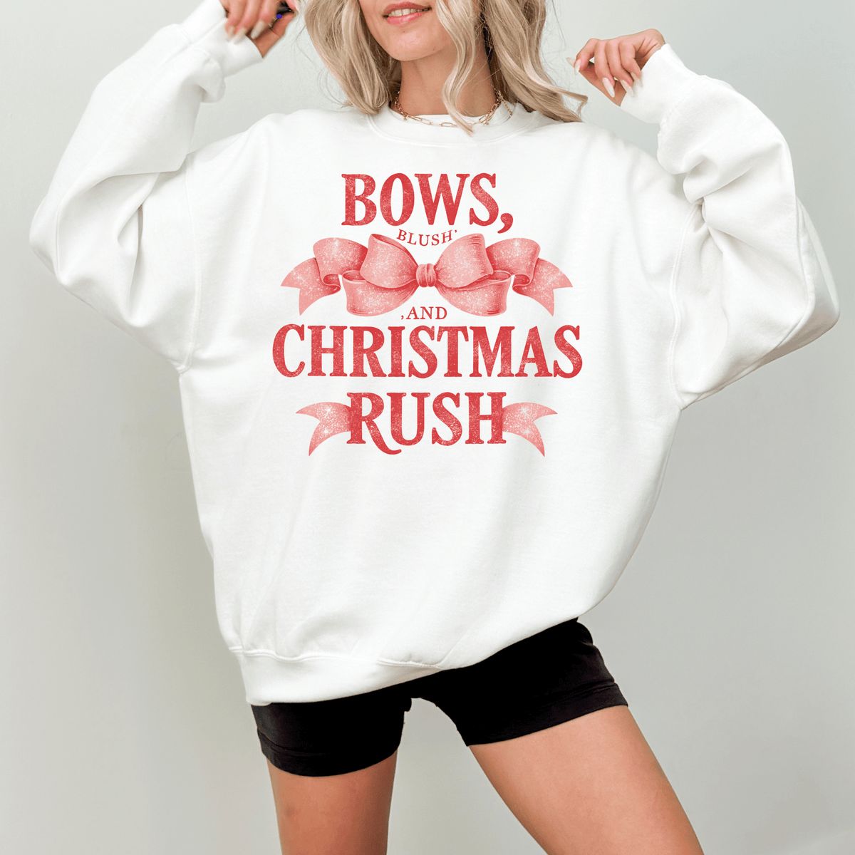 A woman wearing a white sweatshirt with a red bow and text printed on it.
