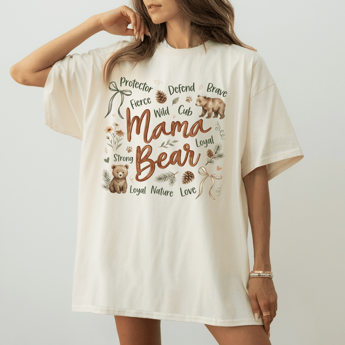 A woman wearing a white t-shirt with a graphic design featuring a bear and various words related to motherhood and nature.