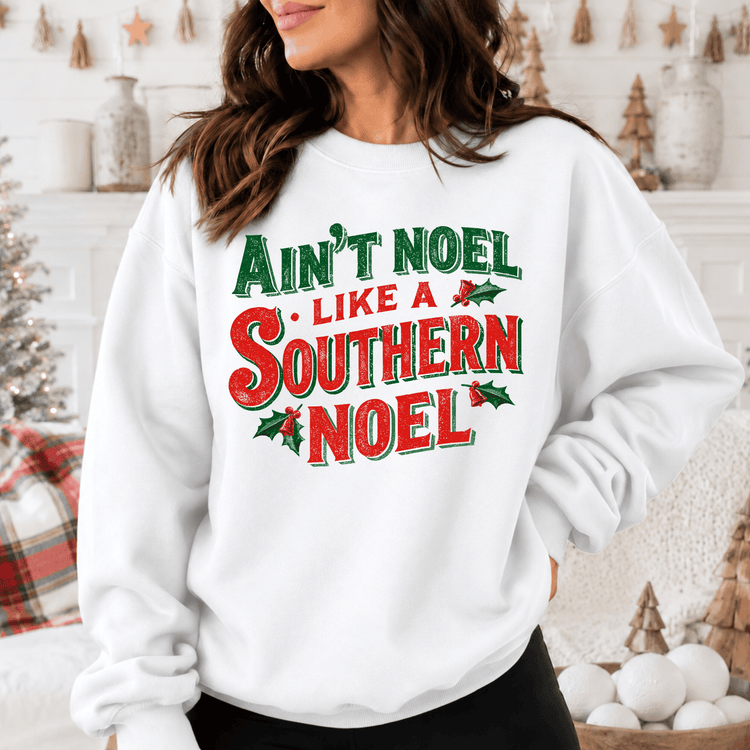A woman wearing a white sweatshirt with a Christmas-themed design.