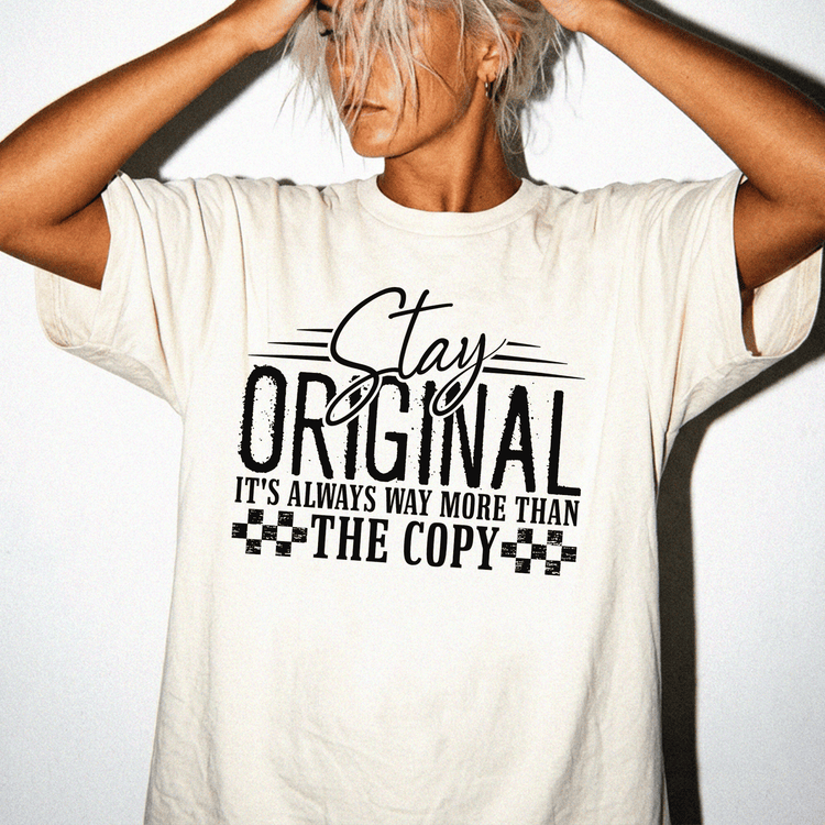A person wearing a white t-shirt with the text "Stay Original It's Always Way More Than The Copy" printed on it.