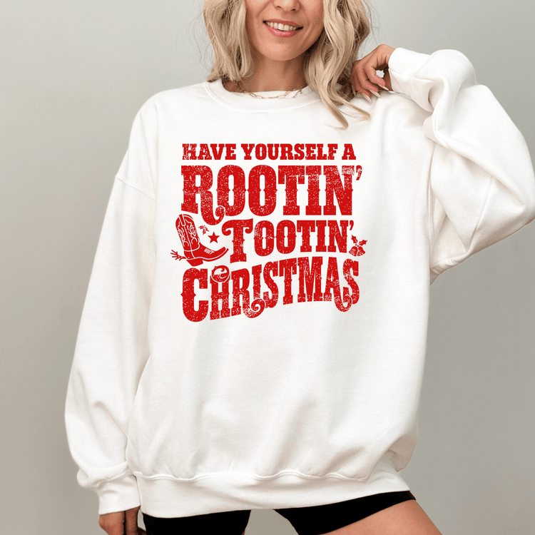 A woman wearing a white sweatshirt with a red and white graphic design that says "Have Yourself a Rootin' Tootin' Christmas".
