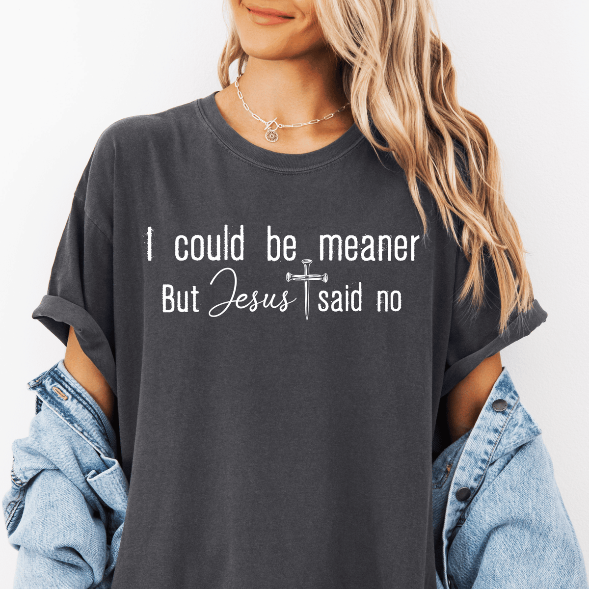 A woman wearing a gray t-shirt with the text "I could be meaner but Jesus said no" printed on it.