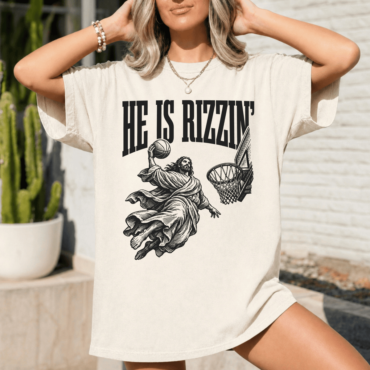 A woman wearing a white t-shirt with a graphic design depicting a basketball player in a religious pose.
