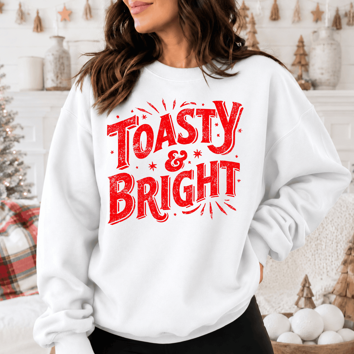 A woman wearing a white sweatshirt with the text "Toasty & Bright" printed on it.