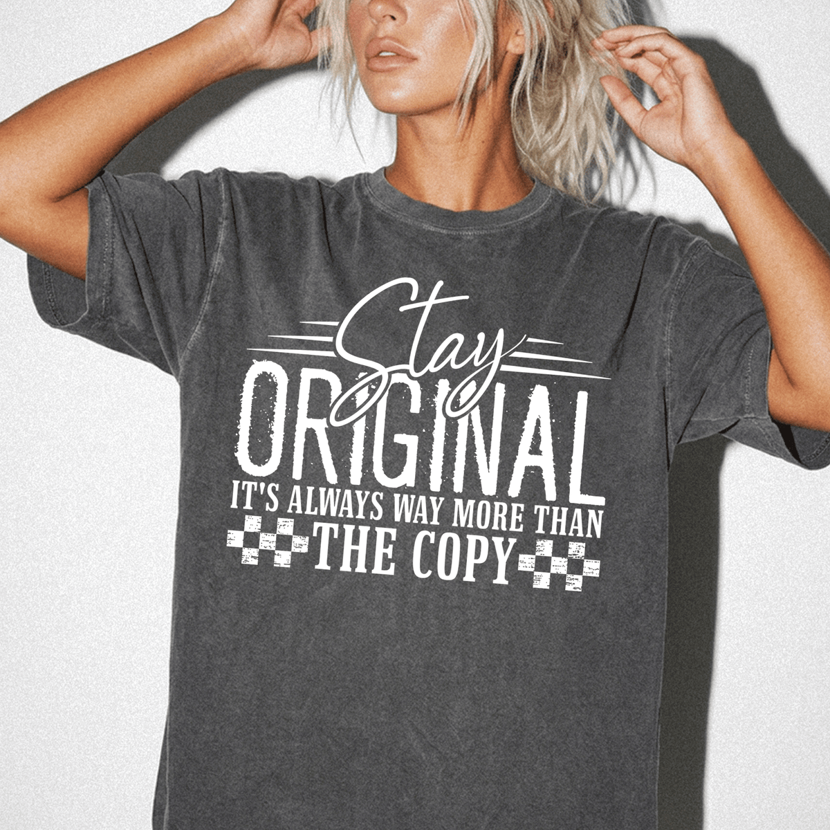 A woman wearing a gray t-shirt with the text "Stay Original It's Always Way More Than The Copy" printed on it.