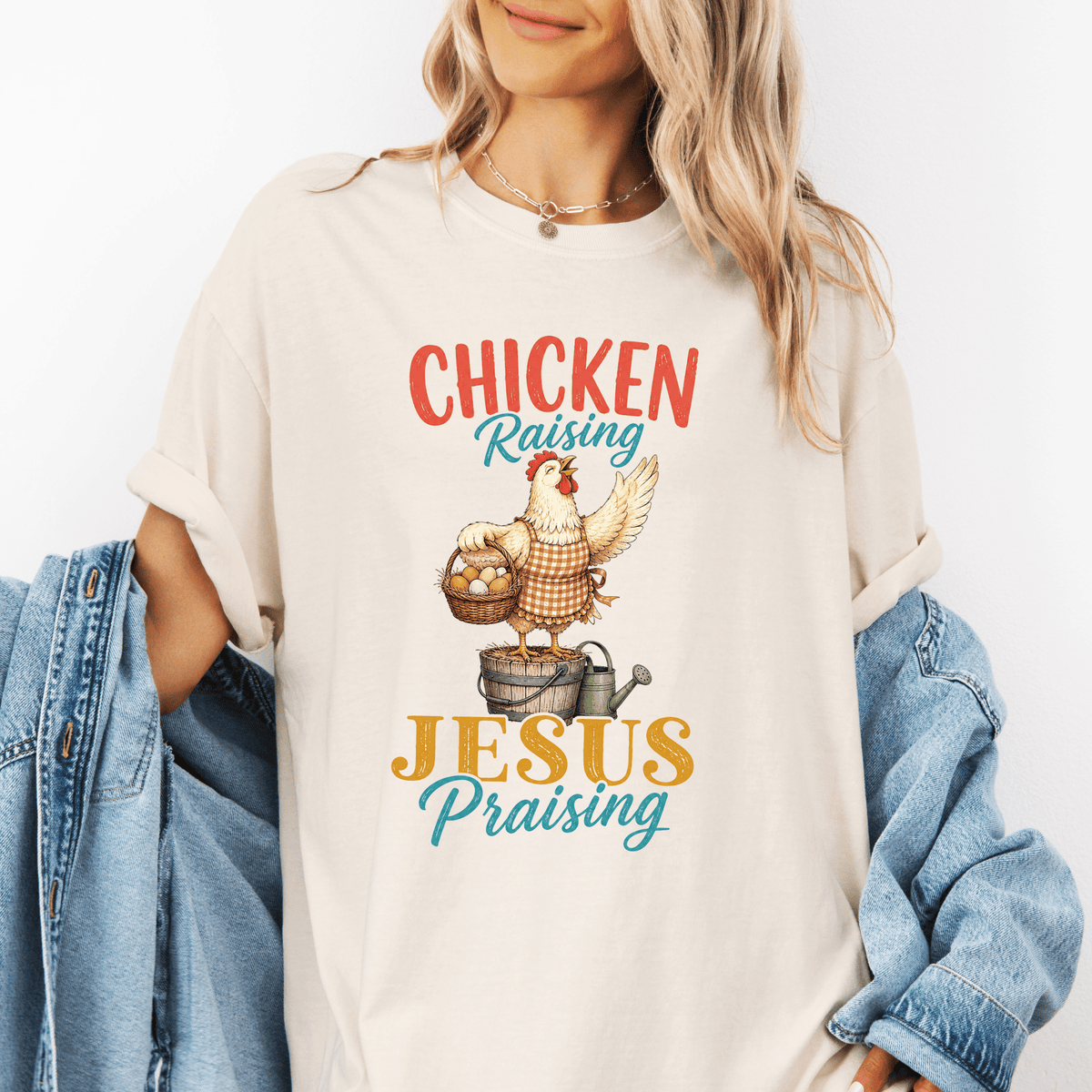 A woman wearing a white t-shirt with a graphic design of a chicken and the text "CHICKEN RAISING JESUS PRAISING" printed on it.