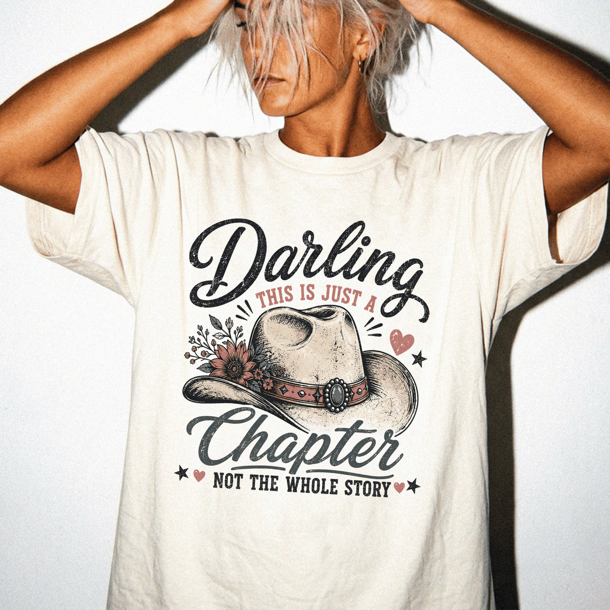 A woman wearing a white t-shirt with a graphic design that says "Daring this is just a chapter NOT the whole story".