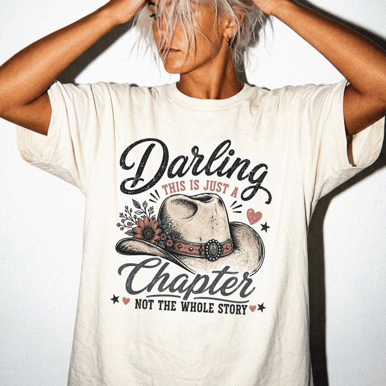 A woman wearing a white t-shirt with a graphic design that says "Daring this is just a chapter NOT the whole story".