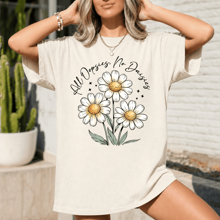A woman wearing a white t-shirt with a graphic design of three white daisies and green leaves.