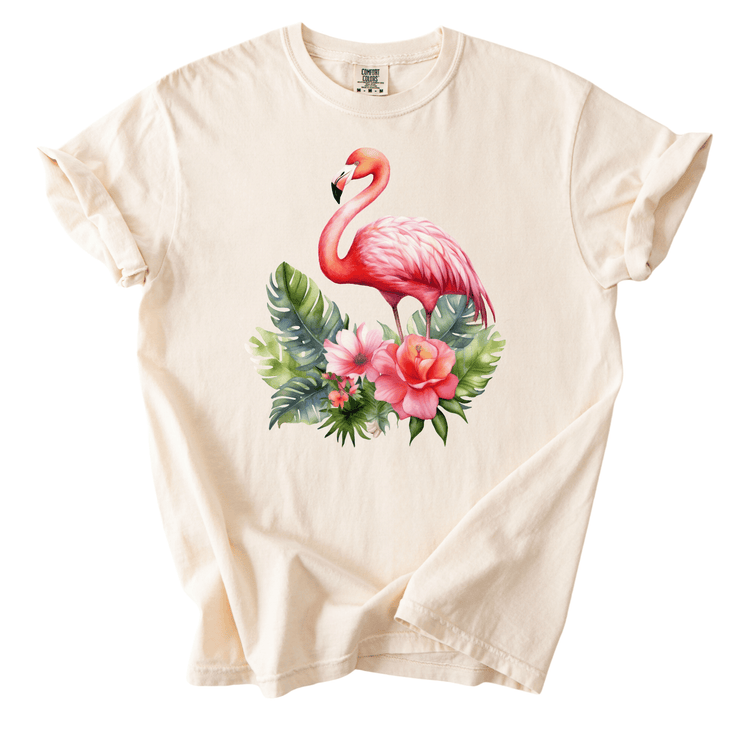 A white t-shirt with a pink flamingo standing on a floral arrangement.