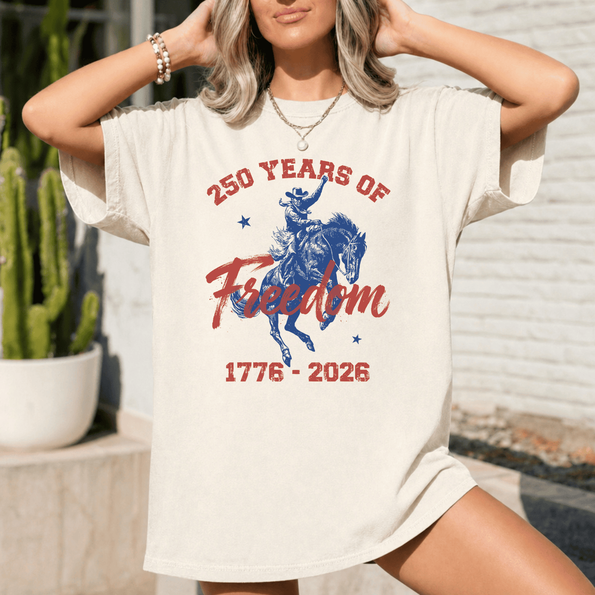 A woman wearing a white t-shirt with a graphic design that says "250 YEARS OF Freedom" and "1776-2026".